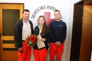 Foto zeigt Anika Körner, die für 15 Jahre aktiven Dienst eine Urkunde und Auszeichnungsspange erhielt.  Eingerahmt vom Bereitschaftsleiter Matthias Körner und seinem Stellvertreter Marian Fochler